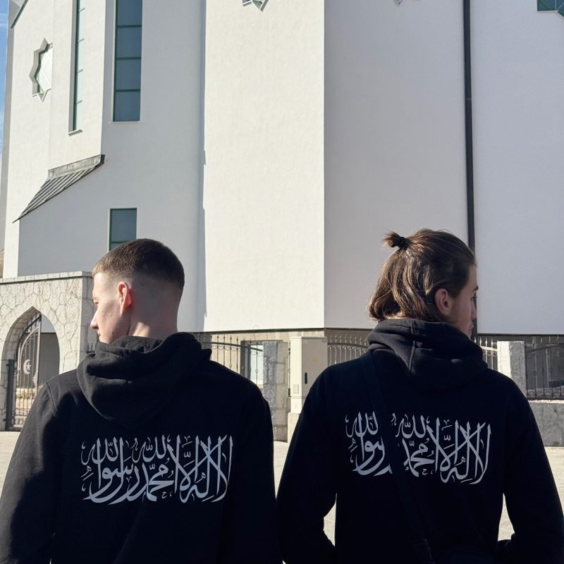 give alt text image Front and back view of a black Shahada hoodie — front reads "No God But Allah" in white text, back features "La Ilaha Illallah Muhammadur Rasulullah" in bold white Arabic calligraphy, Islamic clothing by Ummah Clothing