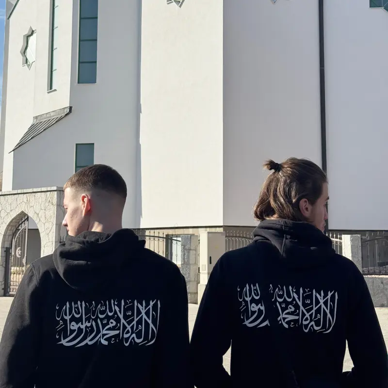 give alt text image Front and back view of a black Shahada hoodie — front reads "No God But Allah" in white text, back features "La Ilaha Illallah Muhammadur Rasulullah" in bold white Arabic calligraphy, Islamic clothing by Ummah Clothing